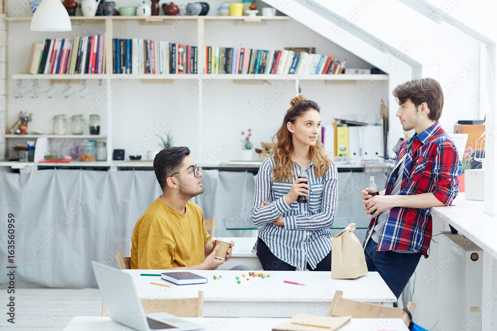 Obraz premium Young people brainstorming and talking while having snack and drinks