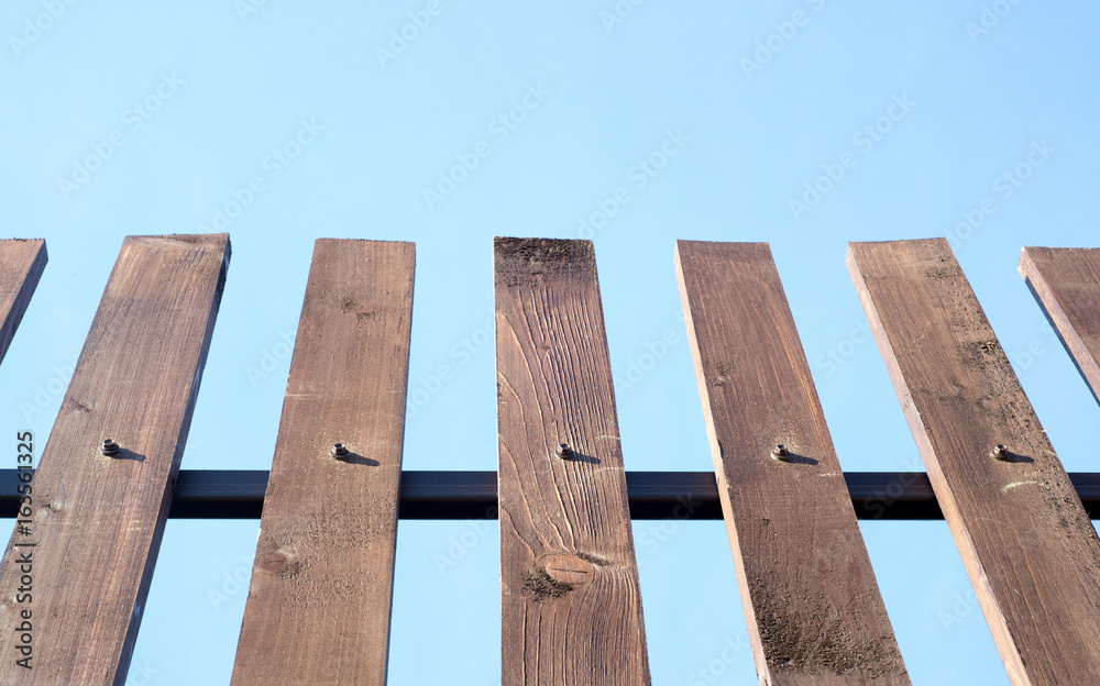 Wooden plank fence on blue sky background Wooden plank fence on blue sky background
