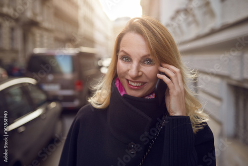 Hübsche blonde Geschäftsfrau telefoniert mit ihrem Handy am morgen