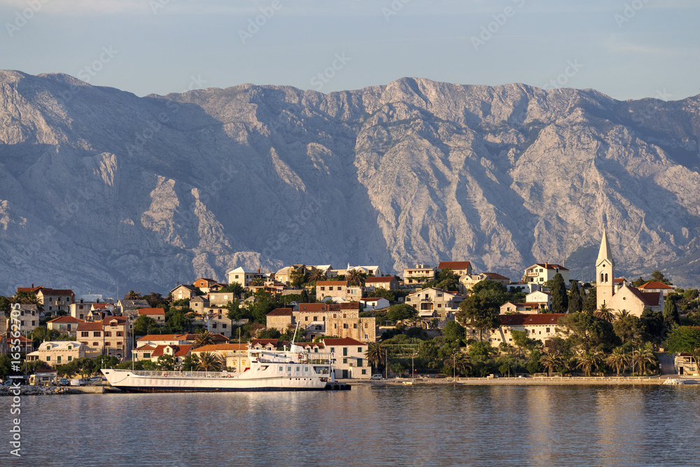 Ferry arrive in picturesque village Sumartin on south-east of Brac island in Croatia, on the background Biokovo mountain