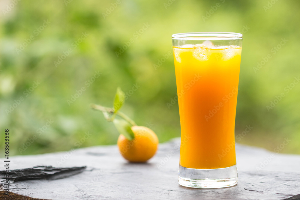 Orange juice on stone plate with nature background , soft focus Orange juice on stone plate with nature background , soft focus