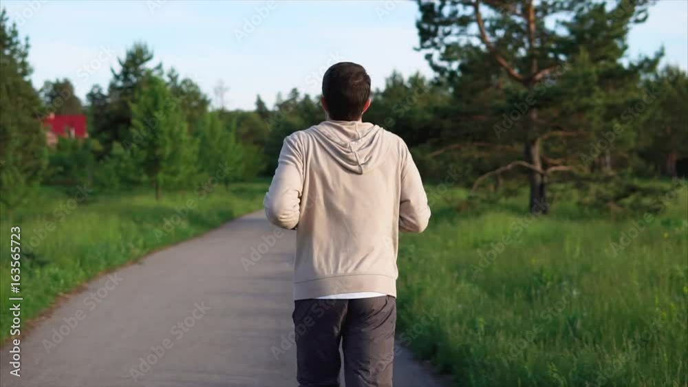Young man running in the park at the track. Sport and healthy lifestyle. Summer time Young man running in the park at the track. Sport and healthy lifestyle. Summer time