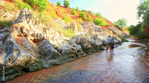 Father Puts Small Girl on Takes from Sand Cliff by Fairy Stream