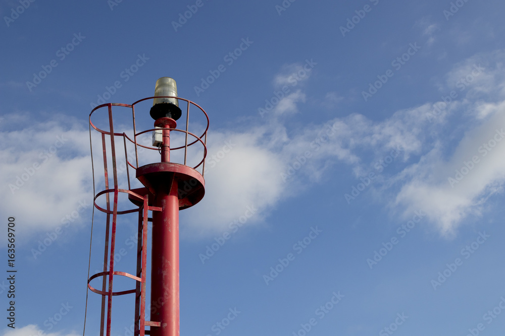 Red top navigation light tower over a blue sky with clouds. Red top navigation light tower over a blue sky with clouds.