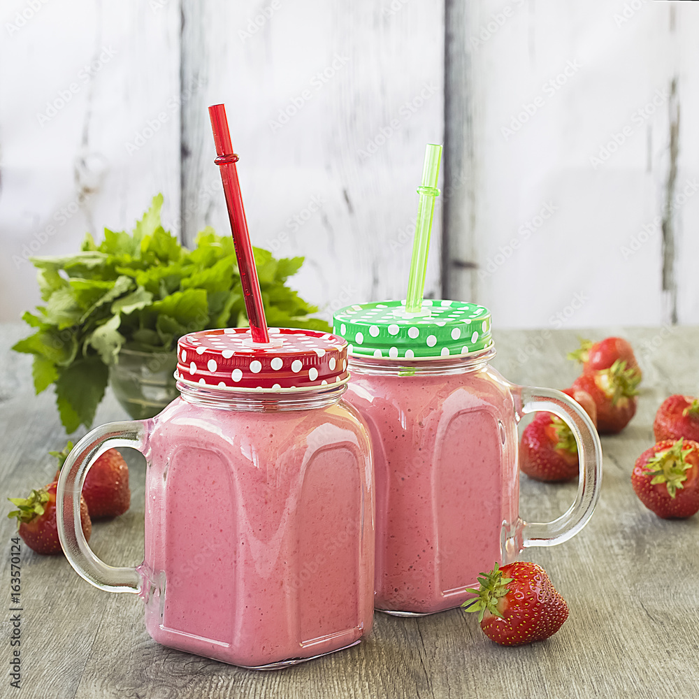 Φωτογραφία Strawberry smoothies in a glass bottle, mint leaves and whole strawberry berries on a gray wooden background