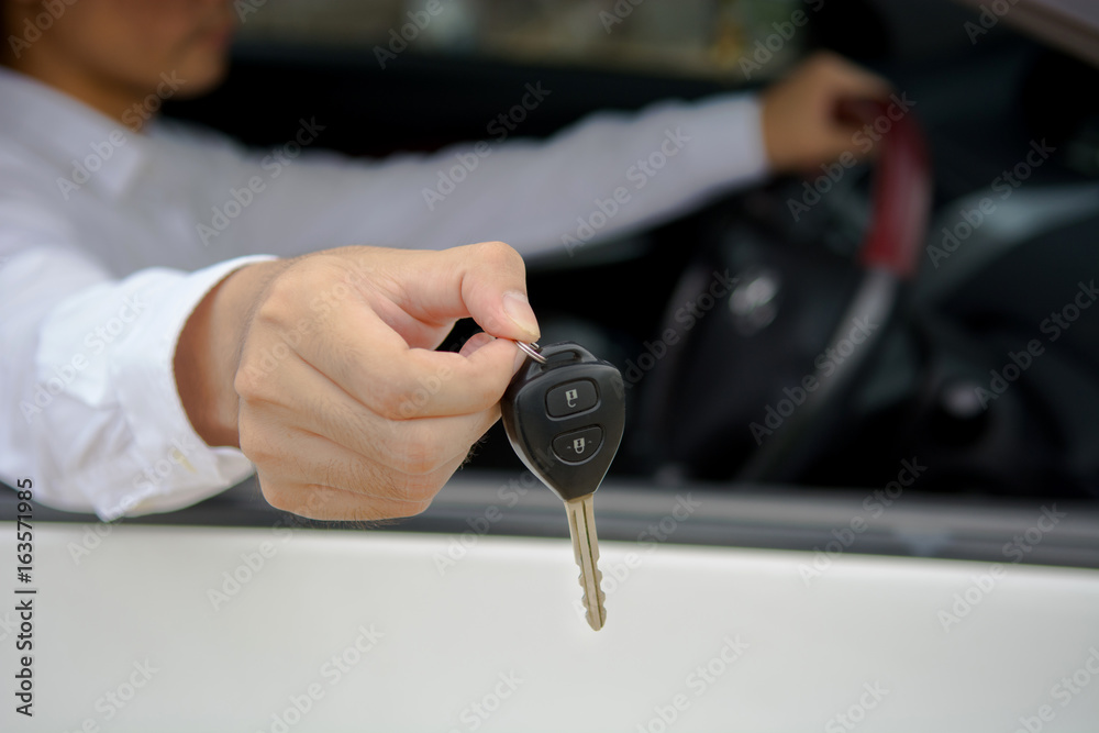 Fototapeta premium Man handing car key while sitting in the car, car for sale or for rent concept.