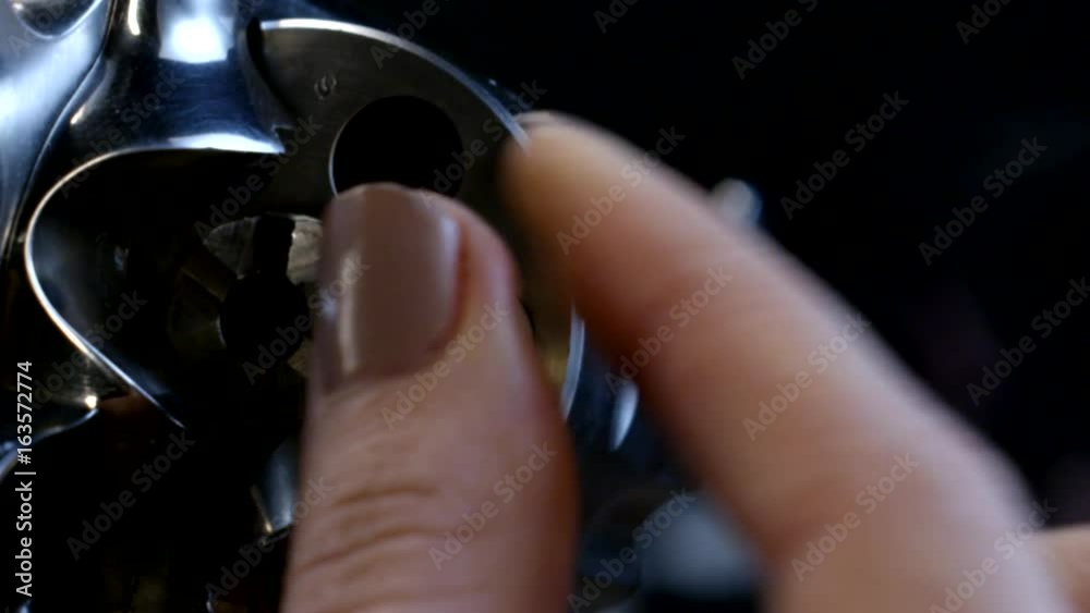 Female fingers inserting the bullet into the revolver drum Female fingers inserting the bullet into the revolver drum
