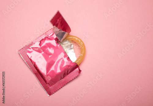 pink condom isolated on pink background photo, hiv prevention concept