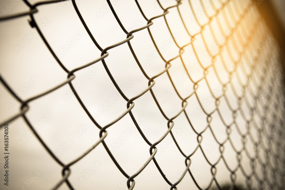Fototapeta premium Vintage tone of wire mesh fence fenced plot with sunshine in sky.