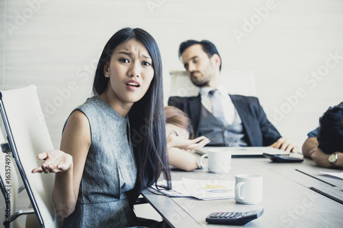 Asian woman feeling unhappy with team, team connot work with her, business overtime concept, 20-30 years old, vintage tone. photo