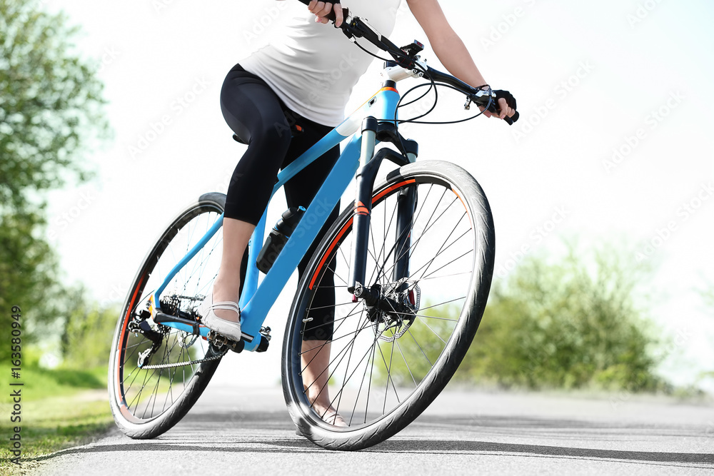Sporty female cyclist with bicycle outdoors on sunny day Sporty female cyclist with bicycle outdoors on sunny day