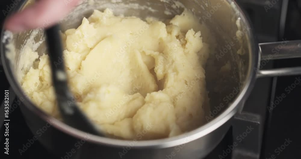 Handheld shot of mixing flour with butter mix for making choux dough Handheld shot of mixing flour with butter mix for making choux dough