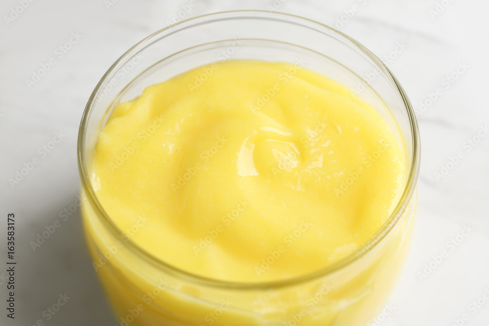 Glass jar with yummy lemon curd on light background Glass jar with yummy lemon curd on light background