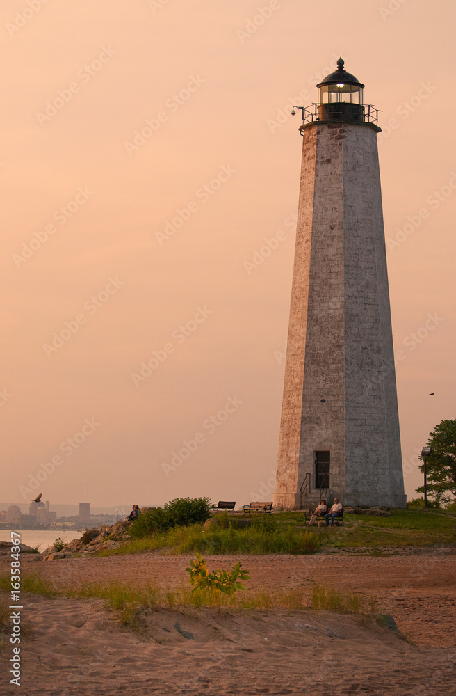 Relaxing at dusk as sun sets by File Mile Point Lighthouse near New Haven in Connecticut.