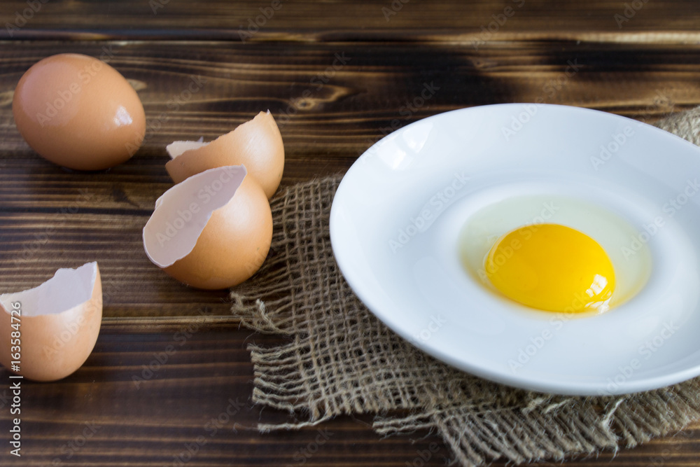 Egg yolk and egg shell on the brown wooden background Egg yolk and egg shell on the brown wooden background