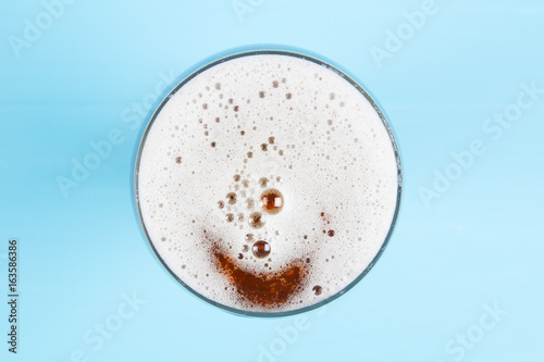 Beer in glass. Beer foam. View from above on blue background. 