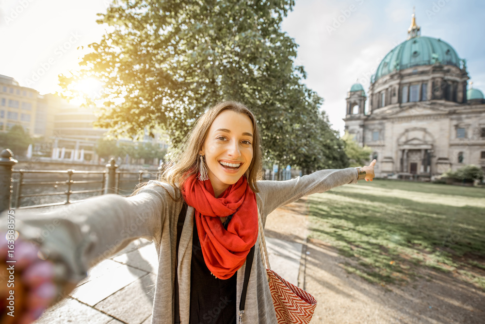 Fototapeta premium Młodej kobiety turystyczny robi selfie fotografia przed sławną katedrą w Berlińskim mieście