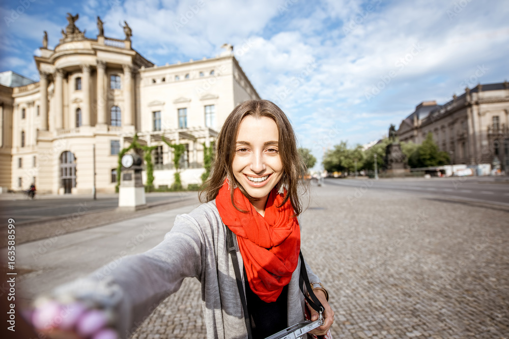 Young woman tourist making selfie photo in front of the old library in Berlin city