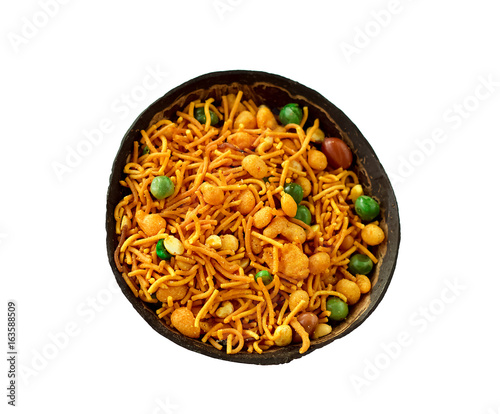 Traditional Indian snack namkeeni in coconut shell cup. A mixture of roasted nuts, puffed rice, dried fruits and roasted grams, seasoned with various spices. Copy space. Isolate