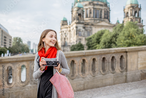 Young woman tourist with photo camera enjoying traveling in Berlin city walking on the old bridge near the famous cathedral photo