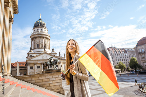 Young woman tourist walking with german flag on the stairs near the Concert house in Berlin
