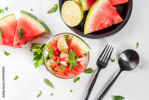 Mexican food. Summer berries and fruits. Vegetable salsa salad with watermelon, tomatoes, onions, greens, lime. In portioned glass on white marble table, with the ingredients. Copy space top view photo