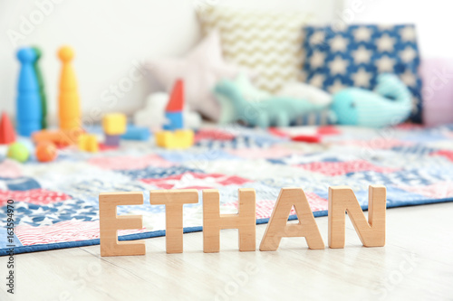 Baby name ETHAN composed of wooden letters on floor. Choosing name concept