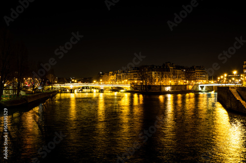 Night urban scene of a calm river crossing a big city © nadrilsan