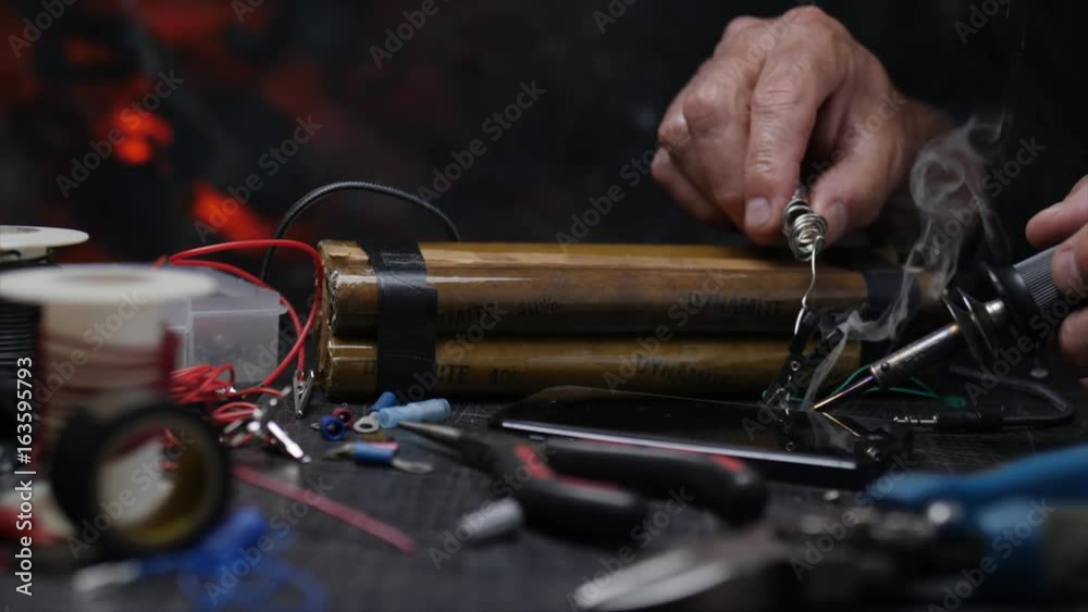 HANDS SOLDERING BOMB CONNECTIONS.  SLOW, CLOSE UP DOLLY MOVE