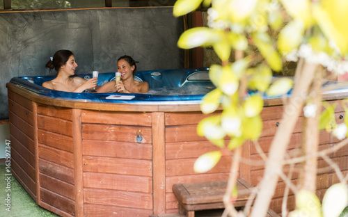 Girls drinking champagne in jacuzzi photo