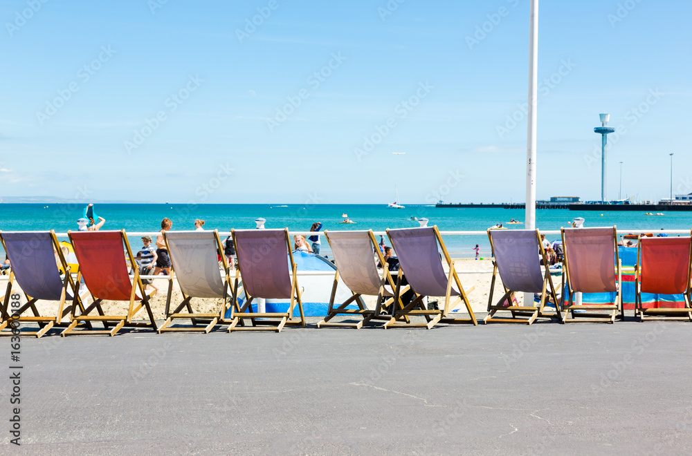 Traditiona wooden deck chairs along promenade in Weymouth, Dorset