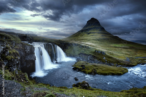 Cloudy overcast day of the Kirkjufellsfoss Waterfall with Kirkjufell mountain in the background in Iceland.