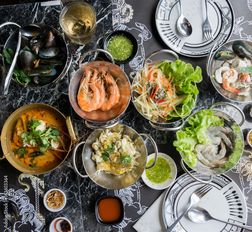Thai seafood on table Include Tom Yum Goong, Papaya salad, Oyster Omelette, Raw shrimp. .