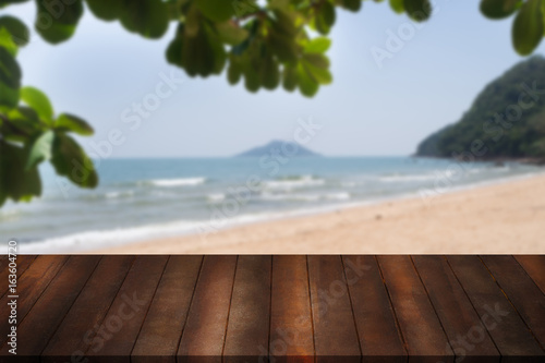 blank wooden shelf with leaf frame on blurry beach and sea. wood stage for showing product.