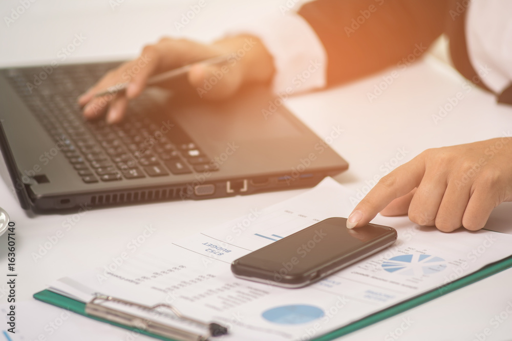 A business woman analyzing investment charts at his workplace and using his laptop and touch smart phone. A business woman analyzing investment charts at his workplace and using his laptop and touch smart phone.