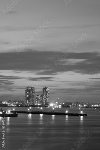 Urban Landscape around bay waters with moving clouds at dusk in monochrome