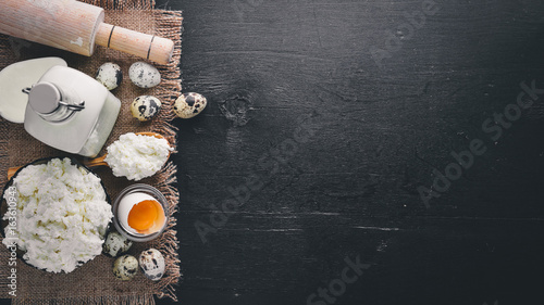 Dairy products. Cheese, cottage cheese, milk, sour cream, on a black wooden background. Top view. Free space. © Yaruniv-Studio