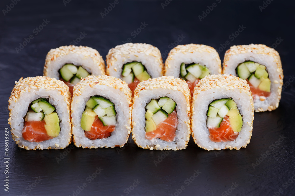 Appetizing fresh california sushi roll with humpback salmon in sesame served on black slate, close up. Japanese healthy seafood Appetizing fresh california sushi roll with humpback salmon in sesame served on black slate, close up. Japanese healthy seafood