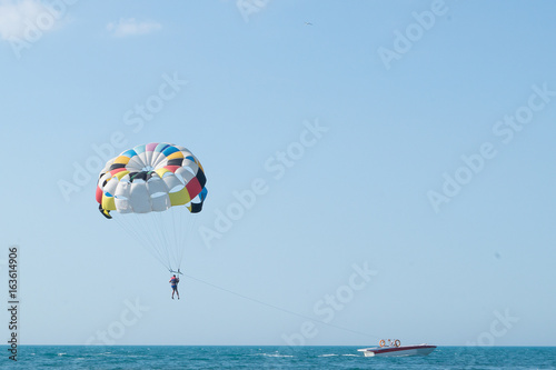 Parasailing is above the sea. Focus on a parachute. Space for text.