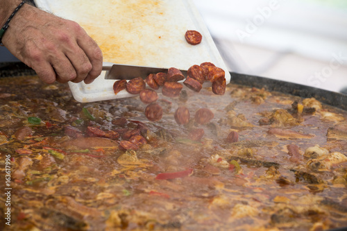 Cooker moving Jambalaya meal in a big paella pan photo