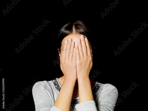 Young woman covering her face with her hands