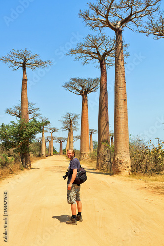 Beautiful Caucasian male tourist with camera at the alley of the Baobabs in Madagascar