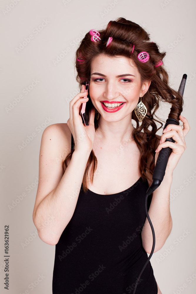 Fototapeta premium girl with hair curlers talking on the phone and makes the hairstyle