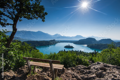 Bench overlooking Bled lake panoramic vista in full summer sun photo