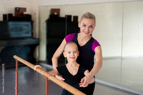 The choreographer teaches the child the ballet positions