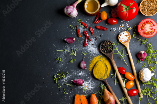 Various spices and vegetables on stone background