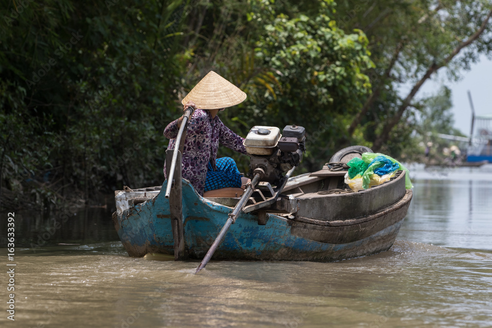 Vietnamese woman on a wooden boat on the Mekong delta.