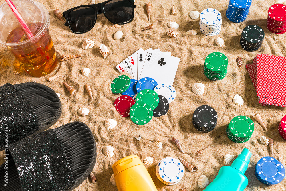 Beachpoker. Chips and cards on the sand. Around the seashells, sunglasses and flip flops. Top view
