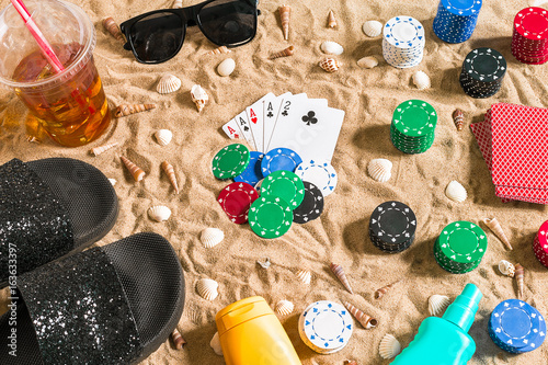 Beachpoker. Chips and cards on the sand. Around the seashells, sunglasses and flip flops. Top view