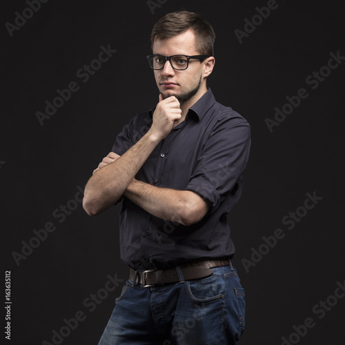 Young pensive man portrait of a confident businessman on a black background. Ideal for banners, registration forms, presentation, landings, presenting concept.